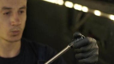 Otomobil tamircisi garajda araba kaldırma makinesinin altında çalışıyor. Otomobil tamirhanesi, araba servisi, tamirat..