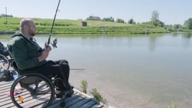 Gölde balık tutan engelli bir adam. Tekerlekli sandalye. Yaz zamanı. Engelli balıkçılığı