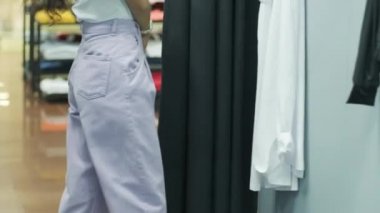 Genç bir kız aynanın yanında giyiniyor. Tatil için kıyafet seçmek ve selfie çekmek.