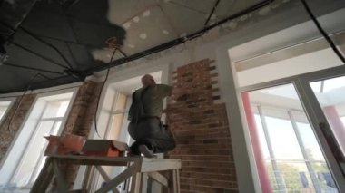 Duvara dekoratif tuğla döşeyen bir uzman. Çatı katı tarzında yenileme. İnşaat çalışmaları