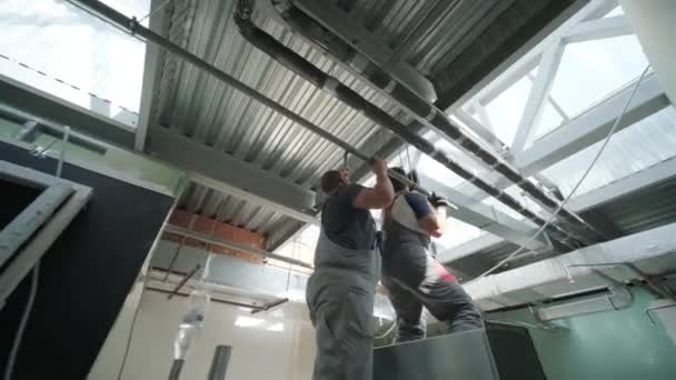 新しいビル内の天井からぶら下がっている銀材料のスカッフォールド組立空気換気シャフトのHvacインストーラー — ストック動画