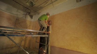 İnşaatçı beton duvarda elektrikli kovalamacayı kesiyor..