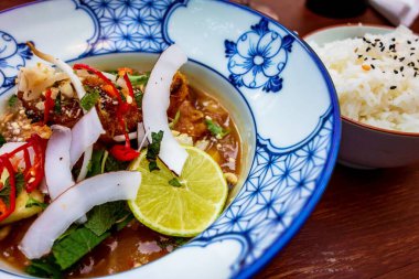 Ekmek kırıntıları içinde deniz balığı, tavadan sebze, kırmızı biber, tatlı ve ekşi soslu ananas ve hindistan cevizi dilimlenmiş limon, ezilmiş fıstıklı ve mavi süslemeli pilav. Asya yemeği, yakın plan..