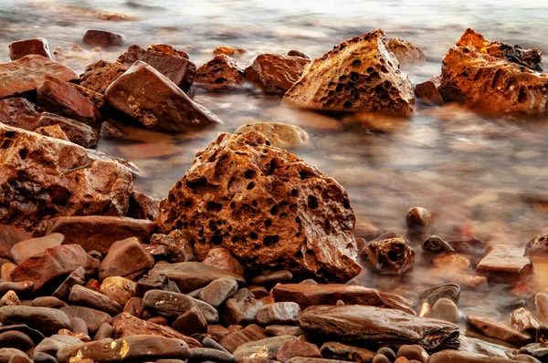Orange stones and pebbles in sea water.