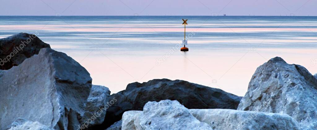 Sunrise on soft sea level with lines,rocks and buoy, panorama