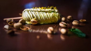 Beyaz çikolata ve fıstıklı lolipop ıslak kahverengi cam arka planda fındık serpiştirilmiş fındıklı fındık, fındık ve yaprak, yakın plan..