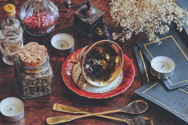 Vintage teacup laying on it's side on a wiccan witch altar for reading tea leaves as a method of divination to foretell the future. Dark moody photo with nature elements and tarot cards in background clipart