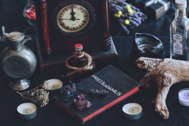 Üzerinde Nostradamus 'un geleceği ve antik Nostradamus kehanetlerini öngörmesiyle ilgili gümüş folyo harfli el yapımı bir kitap. Cadıların arka planı, mumlarla dolu, kurumuş otlar, çiçekler, kavanozlar, şişeler, eski saat ağacı kabuğu.