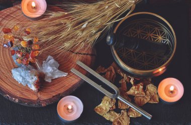 Wiccan cadı sunağı ses iyileştirme büyüsü için 741 saat dayanan çatal ve Tibet şarkı kasesi ile hazırlandı. Kurumuş bitkilerle, çiçeklerle, kristallerle, yanan mumlarla karanlık ahşap bir masada yatıyordu.