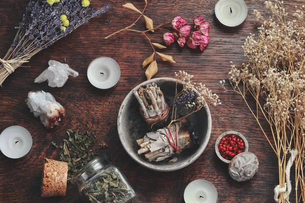 Flat lay of kitchen witchery using herbs and spices found at home. Herbal  magick in wicca and witchcraft. Glass jars filled with dried herbs and  spices, cinnamon, flowers, camomile, burning candles Stock