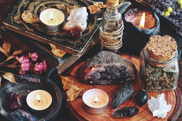 Different types of crystals on wiccan witch altar. Witchcraft themed moody dark photo with various crystals - geode, citrine, quartz cluster, moss agate, kyanite, amethyst, peacock ore, smoky quartz. Burning lit candles in the background