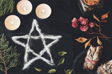 Wiccan cadı sunağında tuz pentagramı sembolü. Cadılık ritüeli için beş köşeli yıldız korunması ve meditasyon. Mumlar, kurumuş çiçekler, adaçayı lekeleri her zaman siyah yüzeyde.