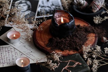 Spell casting on Samhain (Halloween) to contact spirits of dead relatives. Dark and mysterious wiccan witch altar filled with vintage postcards, photos, memorabilia, burning candles, dirt, black earth clipart