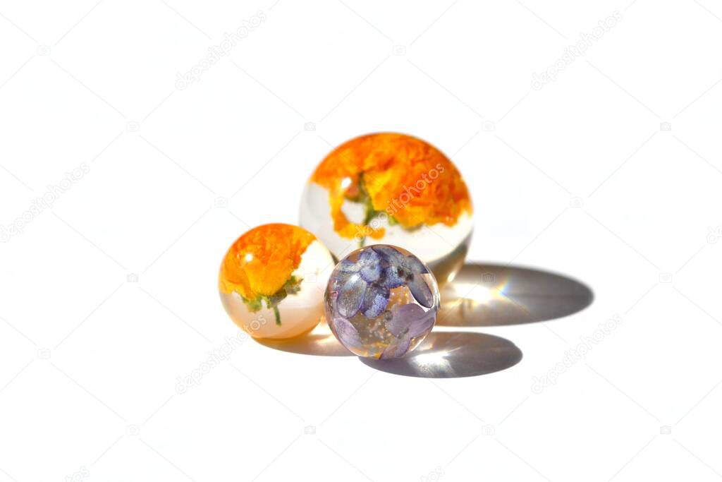 Beautiful colorful background. Handmade violet and orange dried flowers in epoxy resin balls. Isolated on white background, suitable for text insert.