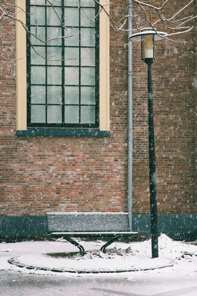 Bench, lamp post and window on a heavy snow day