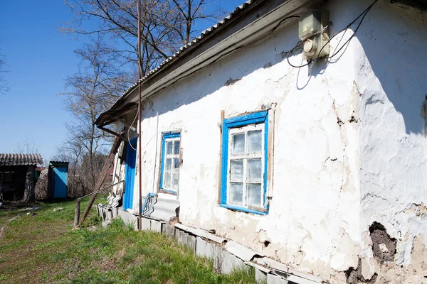 Köyde çiçek açan bahar ağaçlarıyla çevrili eski, düzenli bir ev.