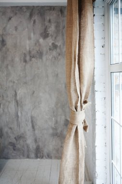 Arka planda çuval bezi perdesi ve gri alçılı duvar. İç mekan. Boşluğu kopyala