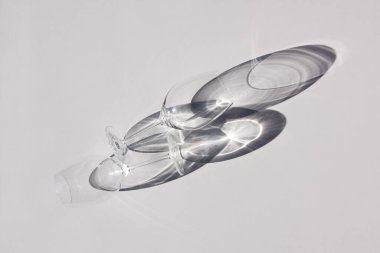 Masada yatan iki şarap kadehi. Soyut gölgeler, güneş ışığı, üst görünüm.