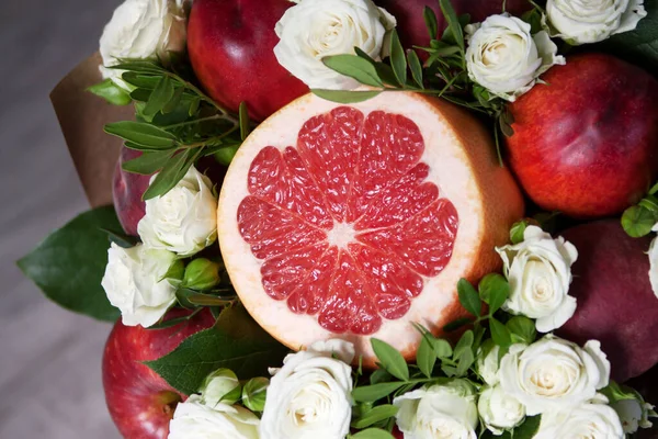 Bir buket meyve ve çiçek. Greyfurt, nektarin, şeftali, beyaz güller ve fıstık. Yakın plan..