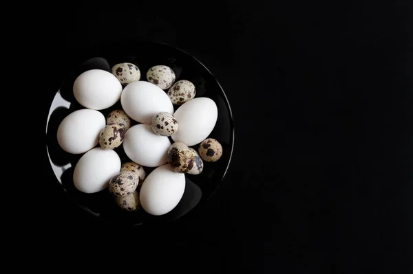 黒い皿の上で鶏とウズラの卵 黒の背景 — ストック写真