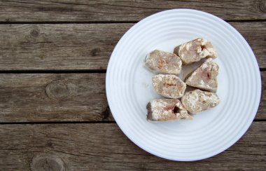 Taze çiğ balık parçaları ahşap bir masada beyaz bir tabakta yatıyor. Balık un içinde çöktü. Yukarıdan bak. Yazıta yer var..