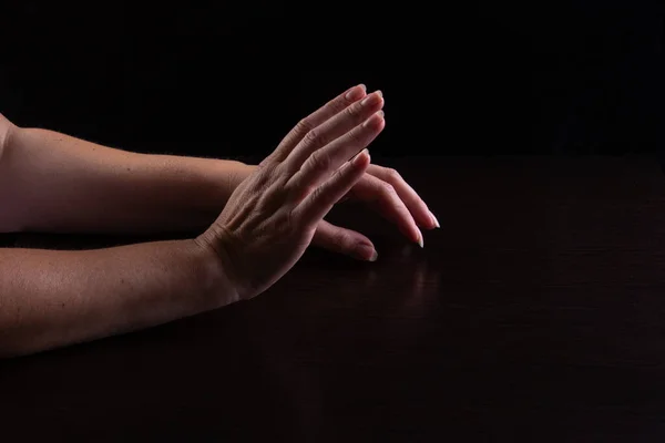 Women\'s hands on the table. Expression of calm dialogue, but hands are showing expression. Low key