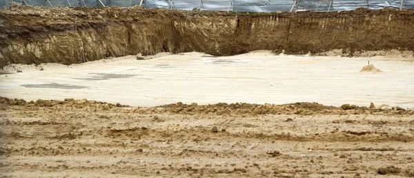 Tesisin inşaatı sırasında kazılan çukurun bir parçası. Yerde, traktörün tırmıkladığı kovanın izlerini görebilirsiniz. Seçici odak.