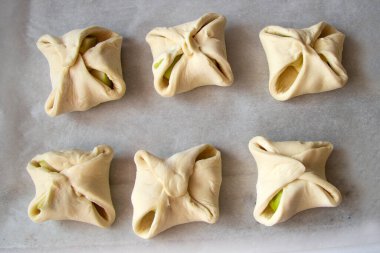 Puf kurabiyeleri ya da elmalı köşeler parşömen kağıdına konur. Çiğ hamur ürünleri pişirmeye hazır. Yukarıdan görüntüle