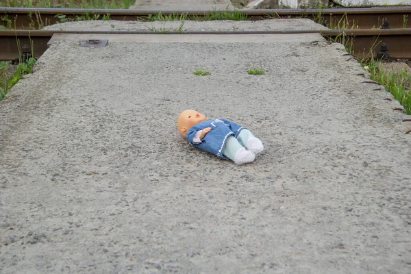 The forgotten doll lies on a concrete slab on the street. Lost toy, missing Stock Picture