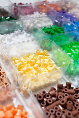 Plastik boncuklar renklerine göre sıralanır. Organizatör konteynırı. Çocukların hobisi. Boncukları ütülüyorum.