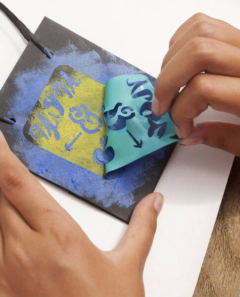 paper bag decorated with stencil. Peeling off the sticker that acts as a stamping template. Craft.