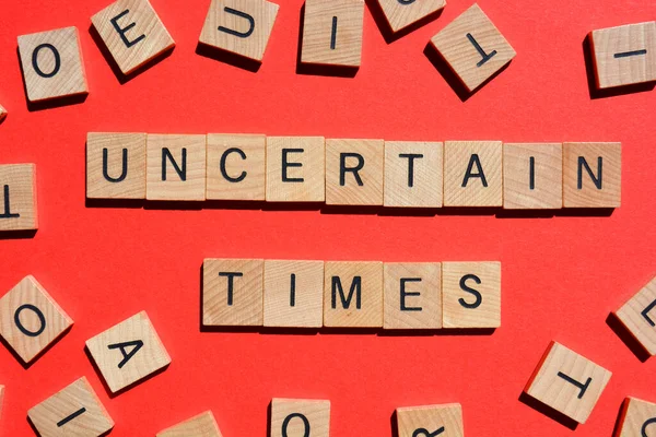 Uncertain Times Wörter Buchstaben Aus Holz Isoliert Auf Rotem Hintergrund — Stockfoto