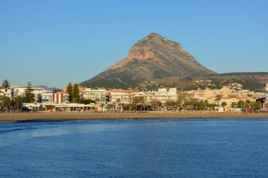 İspanya 'nın Alicante Eyaleti, Costa Blanca' daki Javea tatil köyünde güzel, güneşli ve aydınlık bir sabahta arkasında ikonik Montgo dağıyla Arenal plajına bakın..