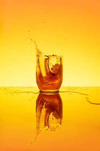 Splashing ice on a glass with fresh drink and lemon