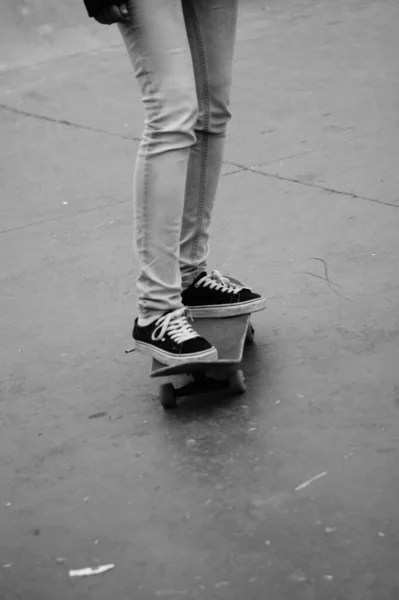 Legs of a girl skating with a skateboard in black and white