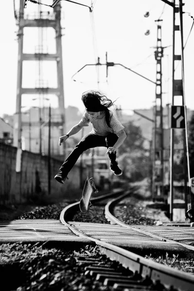 スケーターは黒と白で鉄道の上にトリックをやってる — ストック写真