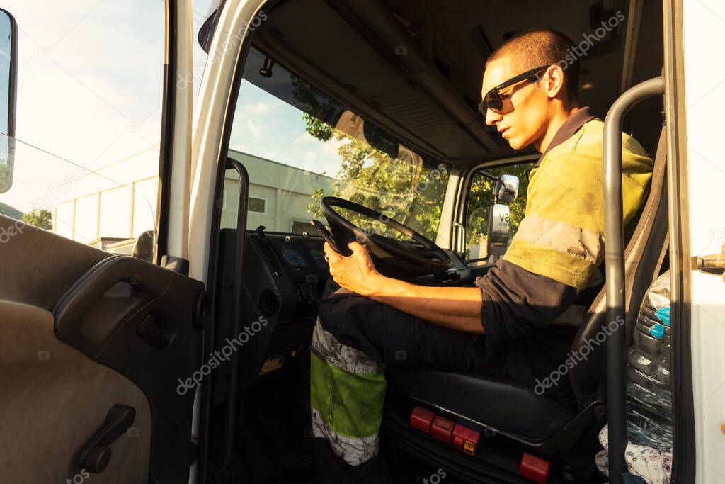 Young man in his truck inside the cabin with the security clothes using the smartphone