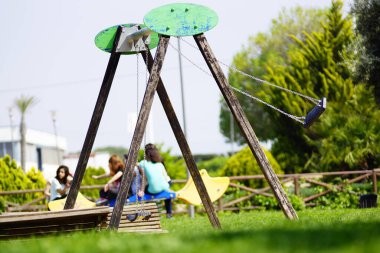 Parkta güneşli bir günde boş bir salıncak.