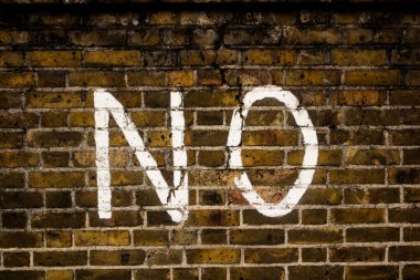 Üzerinde HAYIR yazan eski tuğla duvar.