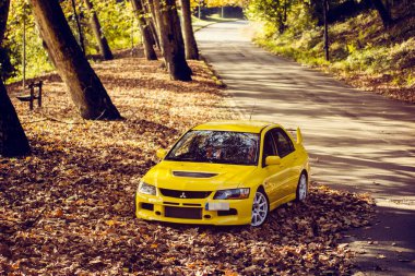 Santander, Cantabria / İspanya, 11-18-2018: Mitsubishi Lancer Evolution 9, sonbahar yapraklarıyla dolu bir dağ yolunda vuruldu
