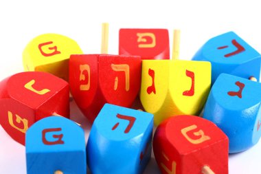 İbranice harflerle beyaz arka planda izole edilmiş renkli dreidler: rahibe, Gimel, He, Pe