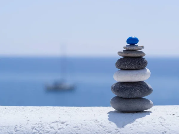 Rock zen pyramid of colorful pebbles on the background of the sea and boat. Concept of Life balance, harmony and meditation