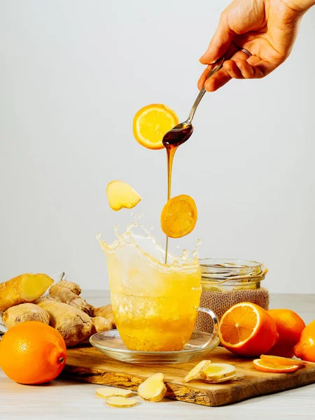 Tahta masada bal ve limonlu zencefilli çay sıçratma, durgun yaşam, havada kalma, kaşıkla el, bal akıyor, kopyalama alanı, dikey yönelim