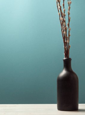 Mavi-yeşil arka planda siyah vazo ve söğüt ile yaşam eğimli, kopya alanı, dikey yönelimli