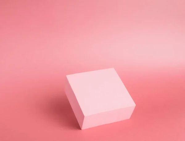 Kağıt zemin üzerinde parlak bir kürsünün (kaide) fotoğrafı. Pembe, değişken ve gölgeli. Reklam yeri. Boş ürün standı ve soyut arkaplan.