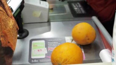 Eldivenli kasiyer kasadaki karpuzları tartıyor.