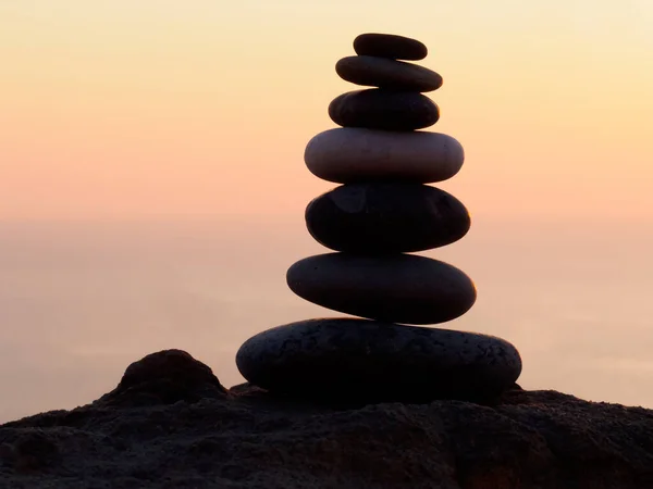 cairn at sunset, stones balances, pyramid of stones at sunset, concept of life balance, harmony and meditation