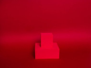 Kağıt bir arka planda iki küpün parlak podyum (kaide) fotoğrafı. Koyu kırmızı ve eğimli. Reklam yeri. Boş ürün standı ve ışık ile soyut arkaplan.