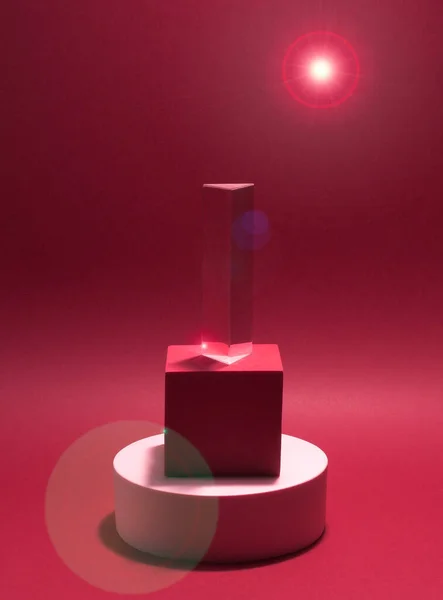 Kağıt zemin üzerinde 3 kaideden (yuvarlak, küp ve prizma) oluşan parlak bir denge. Pembe, eğik ve parıltılı. Reklam yeri. Boş ürün standı ve ışık ile soyut arkaplan.