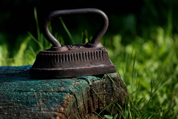 Vintage rusty iron on the green grass background closeup taken.Decoration aged things. Vintage things for home. Craft souvenirs for home and garden.